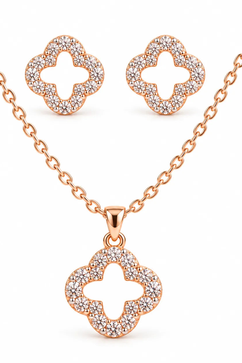 Rose gold jewelry set featuring a clover-shaped pendant necklace, matching stud earrings, and a chain, all adorned with pavé-set clear stones on a white background.
