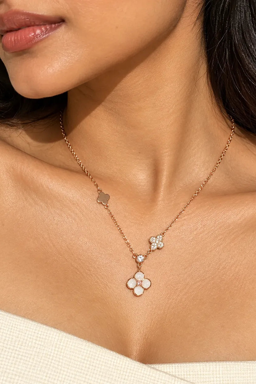 A close-up lifestyle shot of a model wearing a delicate rose gold necklace with a small clover pendant and a small heart-shaped charm.