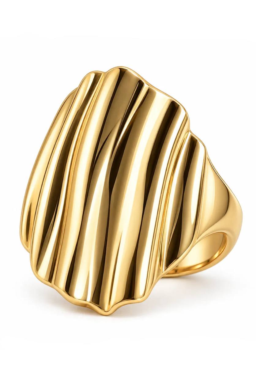 A large, polished gold signet ring with a sculpted, vertically fluted face, shown on a clean white background.